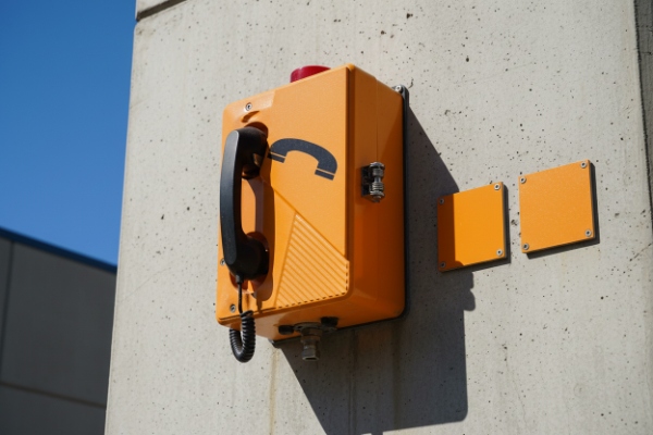 Orange weatherproof SIP emergency phone mounted on concrete pillar with accessory plates