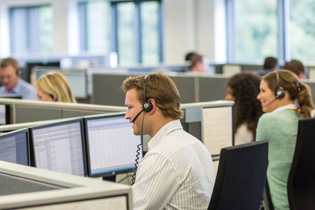 Busy contact center agents wearing VoIP headsets working at computer stations