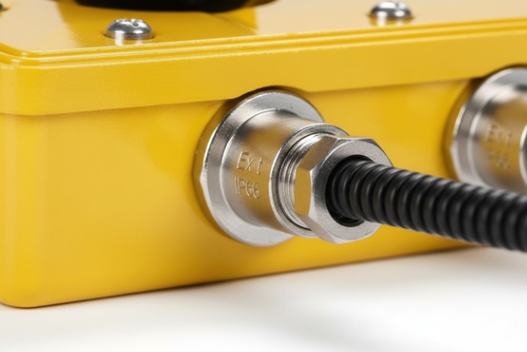 Close-up Ex rated cable gland and flexible conduit entry on yellow enclosure