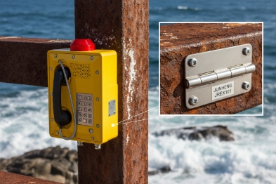 Explosion-proof phone installed on rusted offshore post with close-up stainless hinge plate