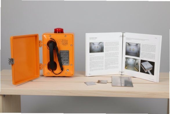 Open SIP emergency phone on desk with test coupons and inspection documents