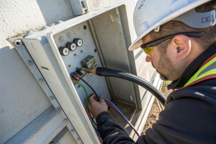 Technician wiring cables inside outdoor emergency call box control enclosure