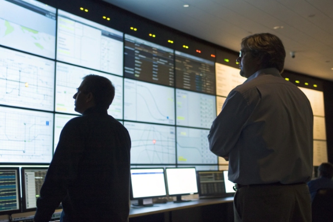 Operations engineers monitoring mission critical systems on large control room video wall