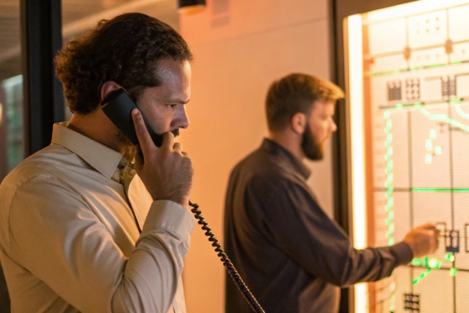 Telecom engineers managing voice network in control room using wall panel
