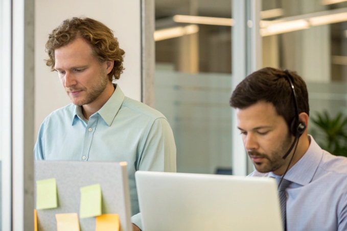 Technical support engineers collaborating at desks with headsets and laptops