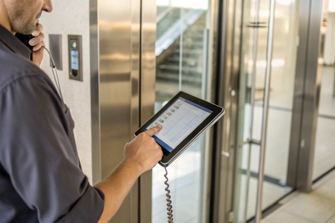 Technician configuring elevator SIP intercom using handheld tablet