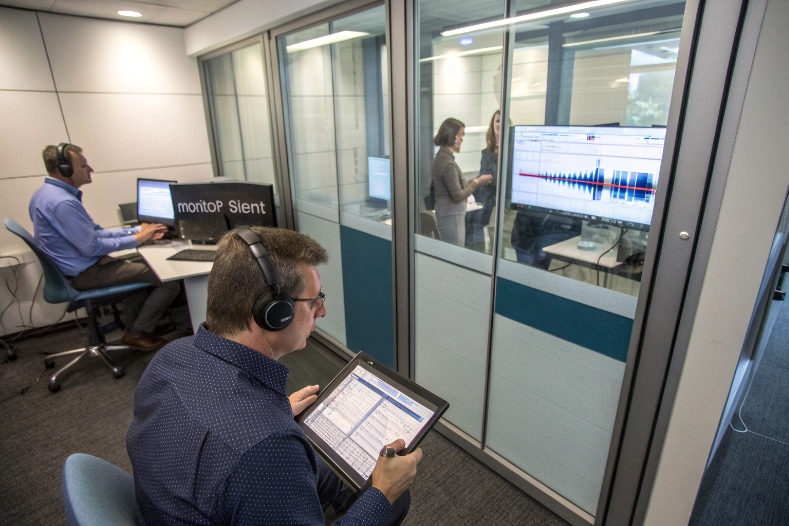 Engineers in audio lab monitoring SIP call quality and acoustic waveforms on screens