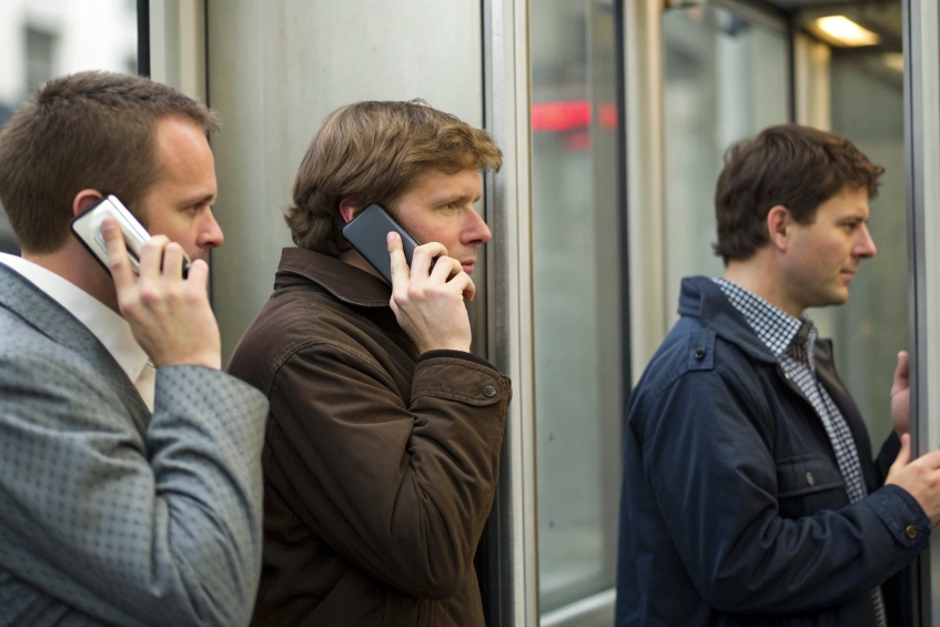 Businessmen making simultaneous mobile calls in urban environment