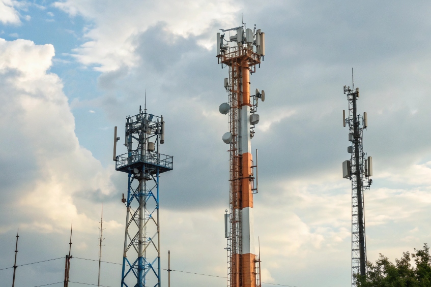 Multiple cellular towers of different designs providing shared wireless coverage under a cloudy sky