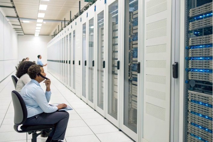 Engineers monitoring large data center racks and network servers